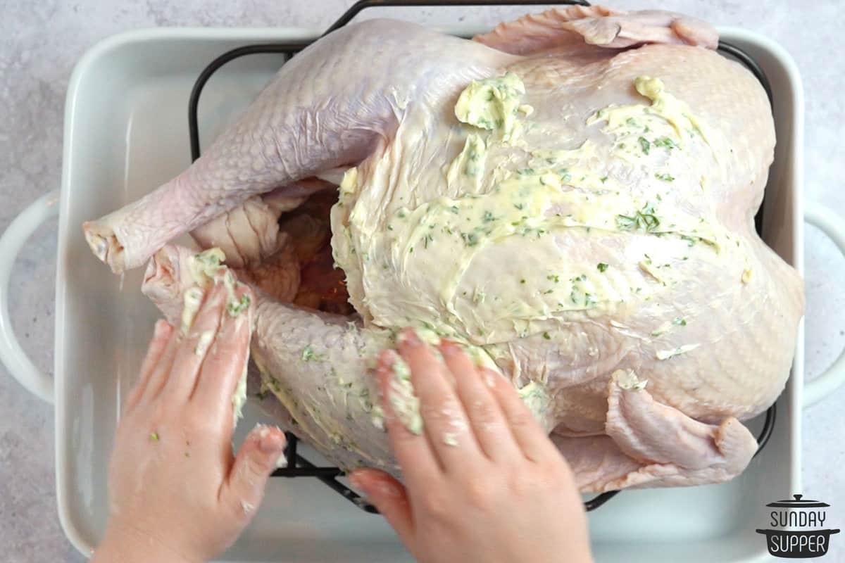 rubbing garlic butter on turkey in a baking pan