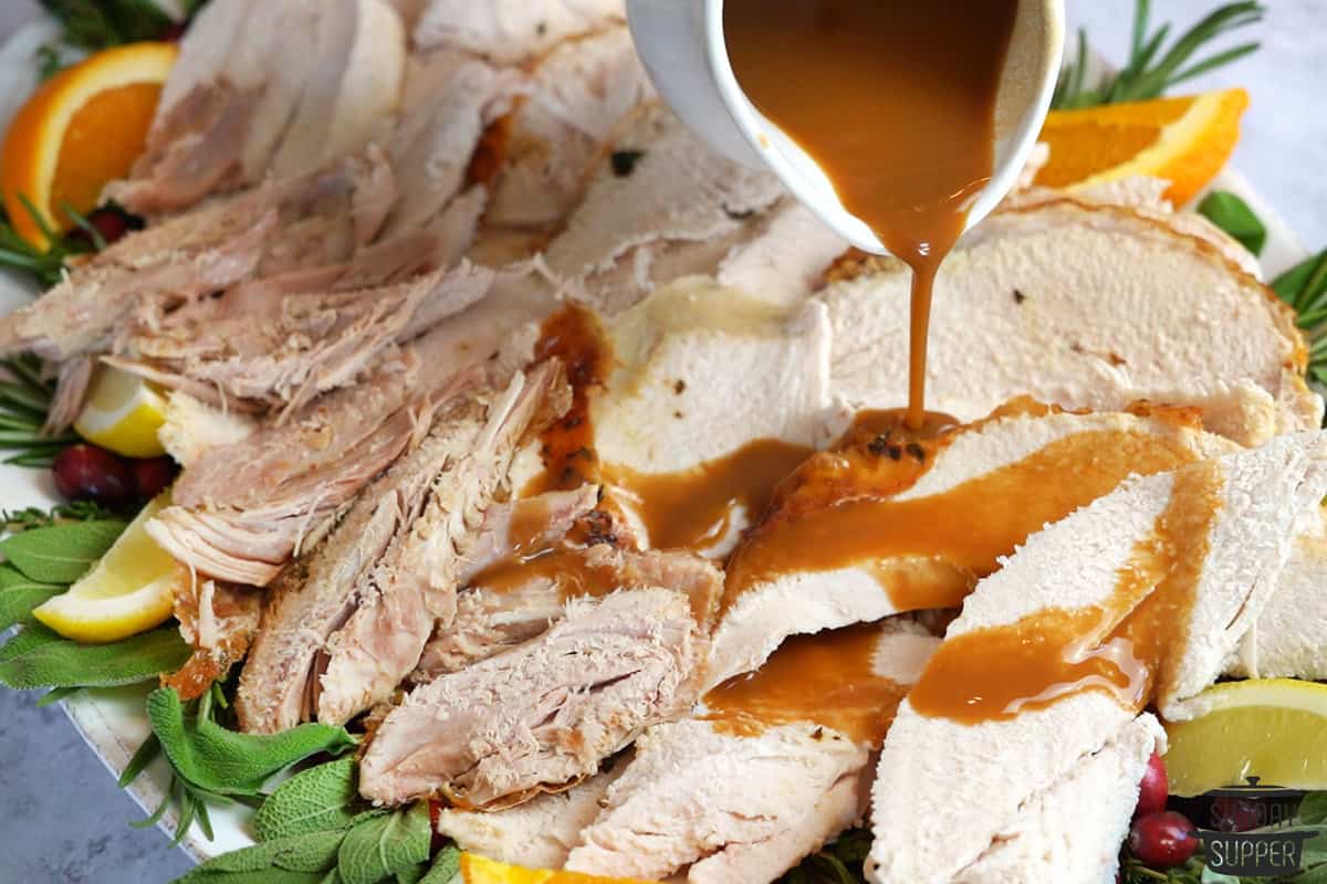 pouring gravy over the sliced turkey
