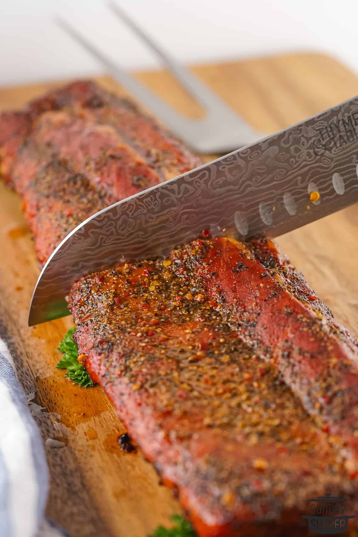 slicing smoked pork ribs with a knife