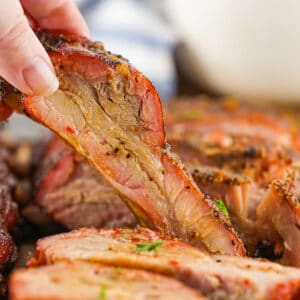 lifting a pork rib away from sliced ribs