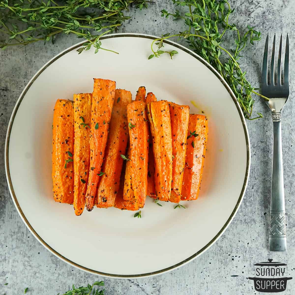 a plate filled with air fried carrots with extra herbs and a fork