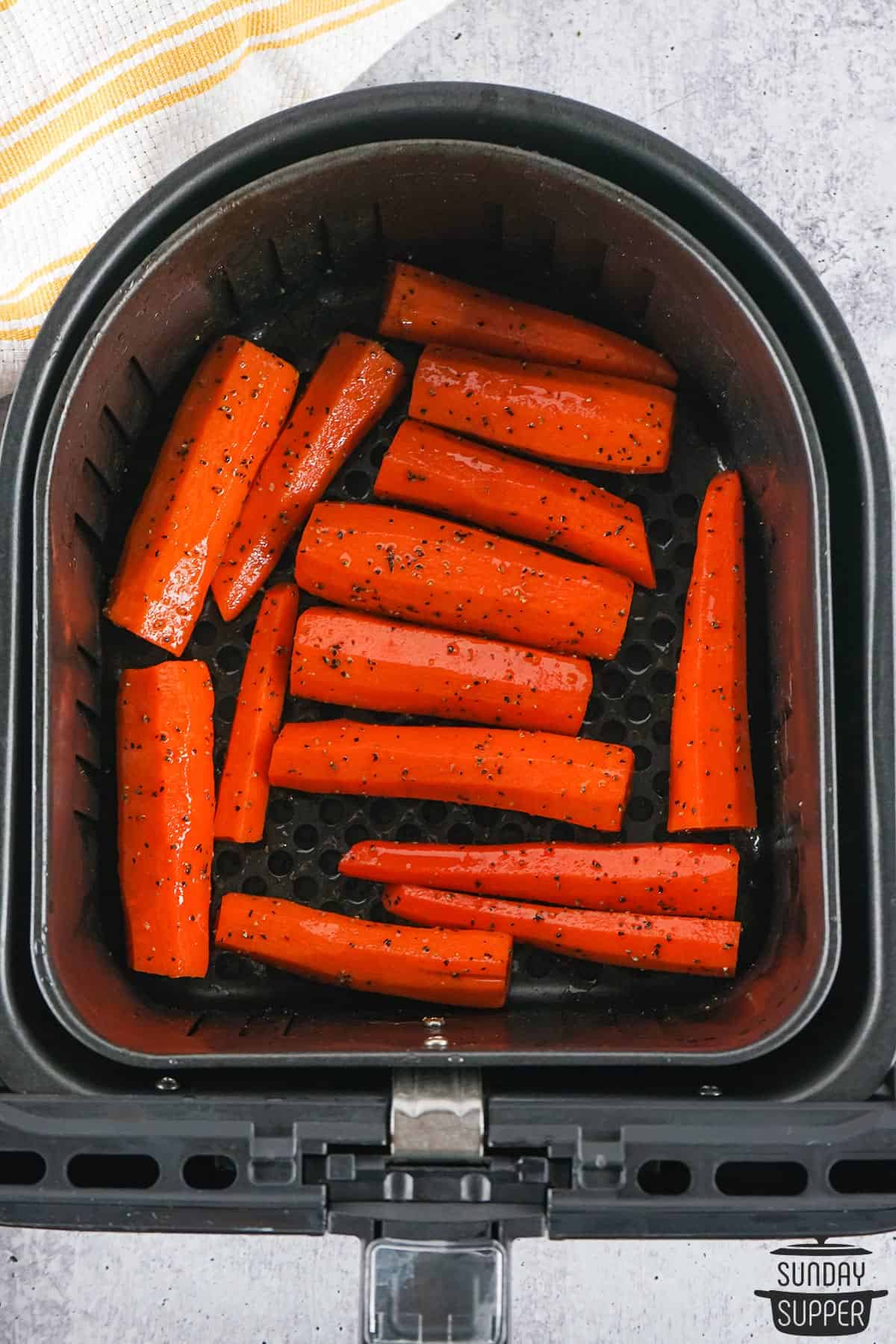 seasoned carrots spread out in an air fryer