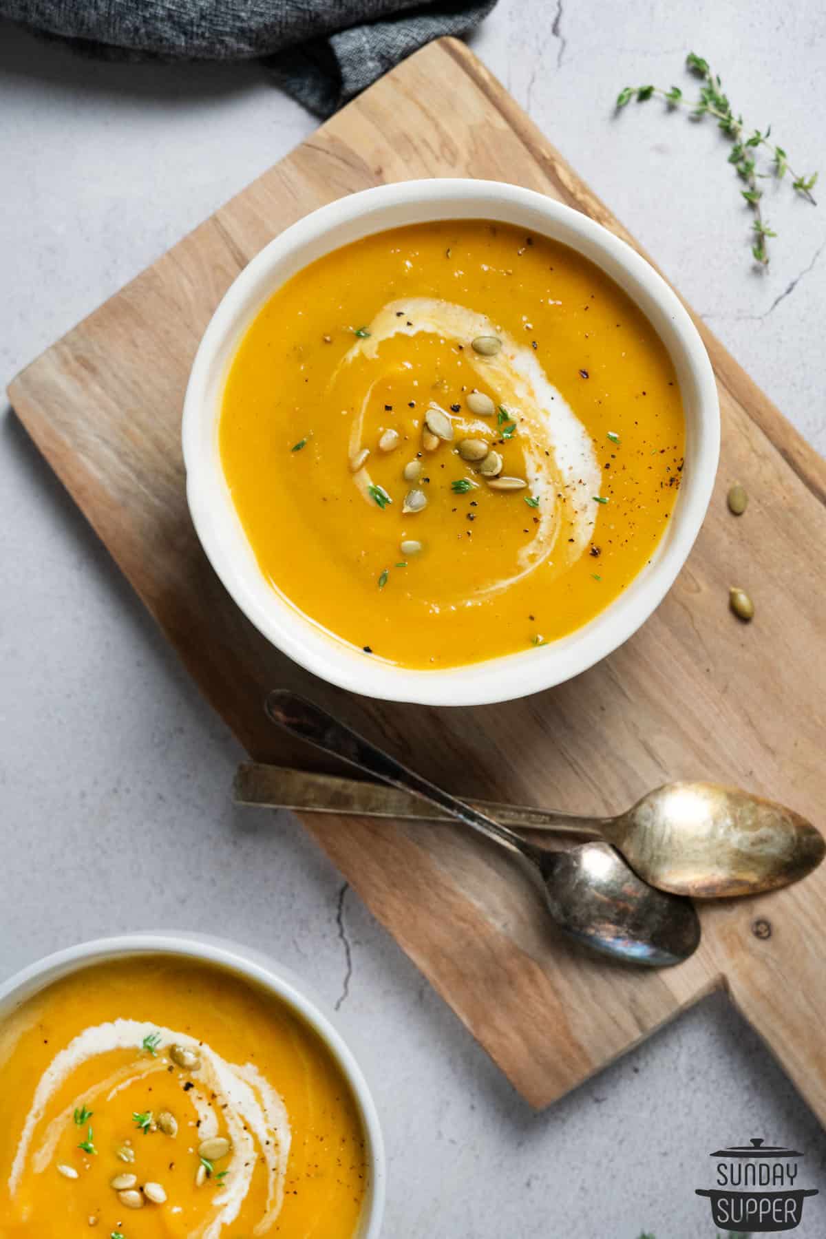two bowls of butternut squash soup with two spoons
