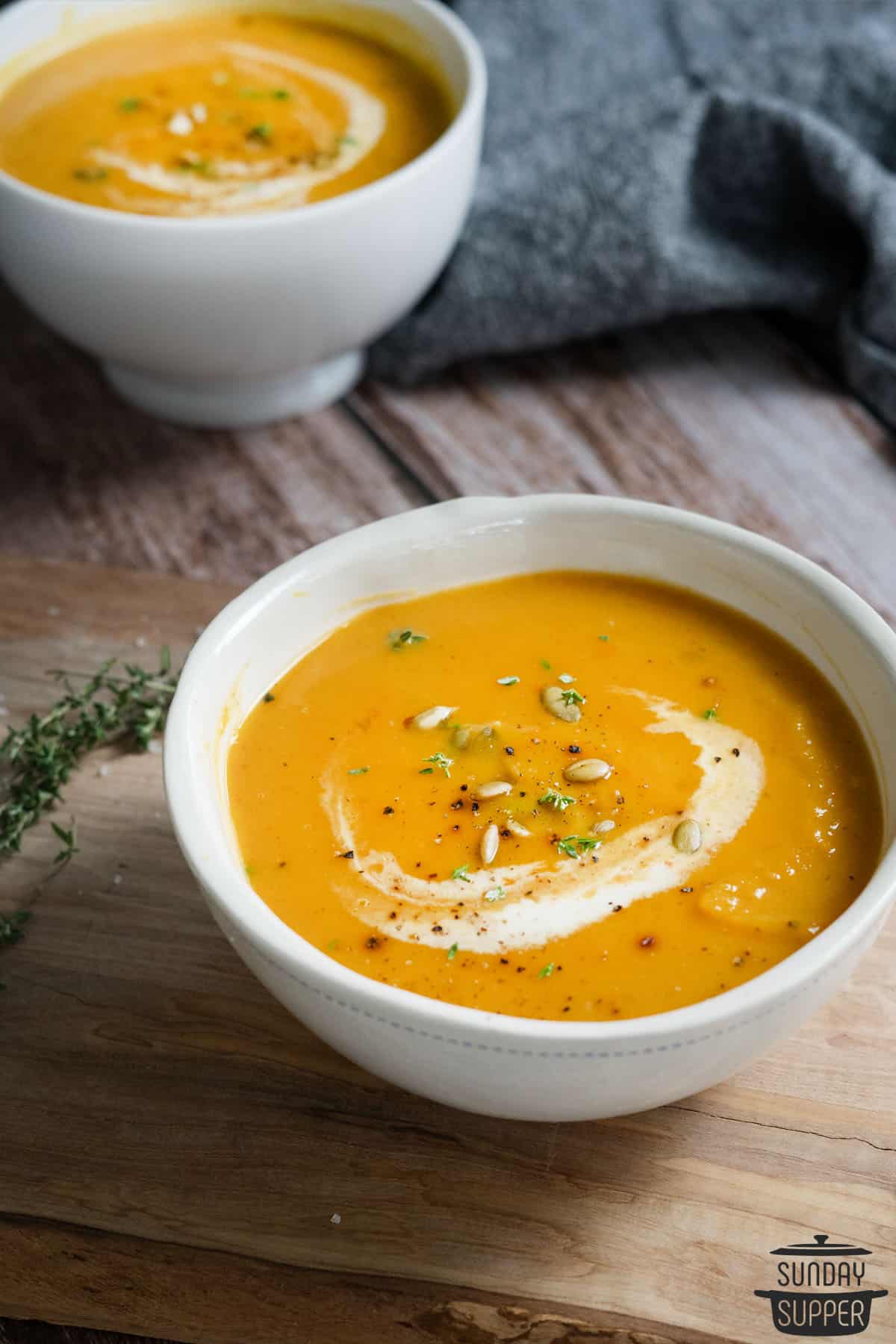 butternut squash soup in a white bowl with wood underneath