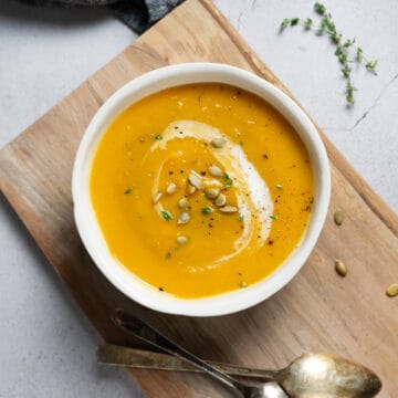 butternut squash soup in a white bowl with pumpkin seeds on top