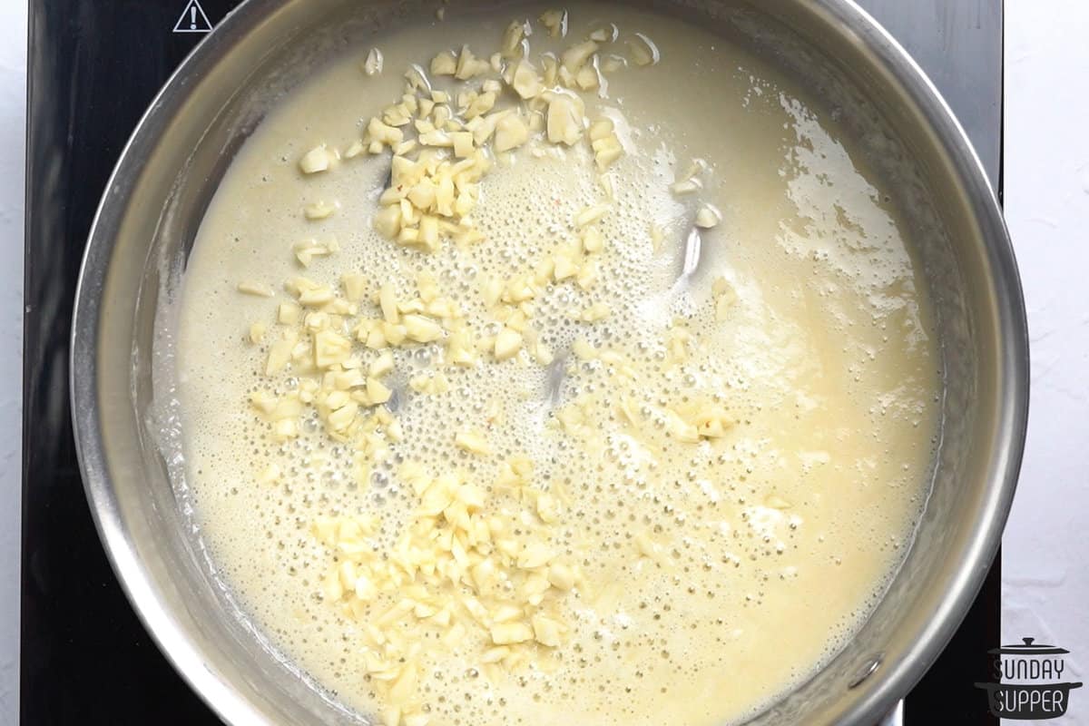 adding garlic to melted butter and flour in a pan