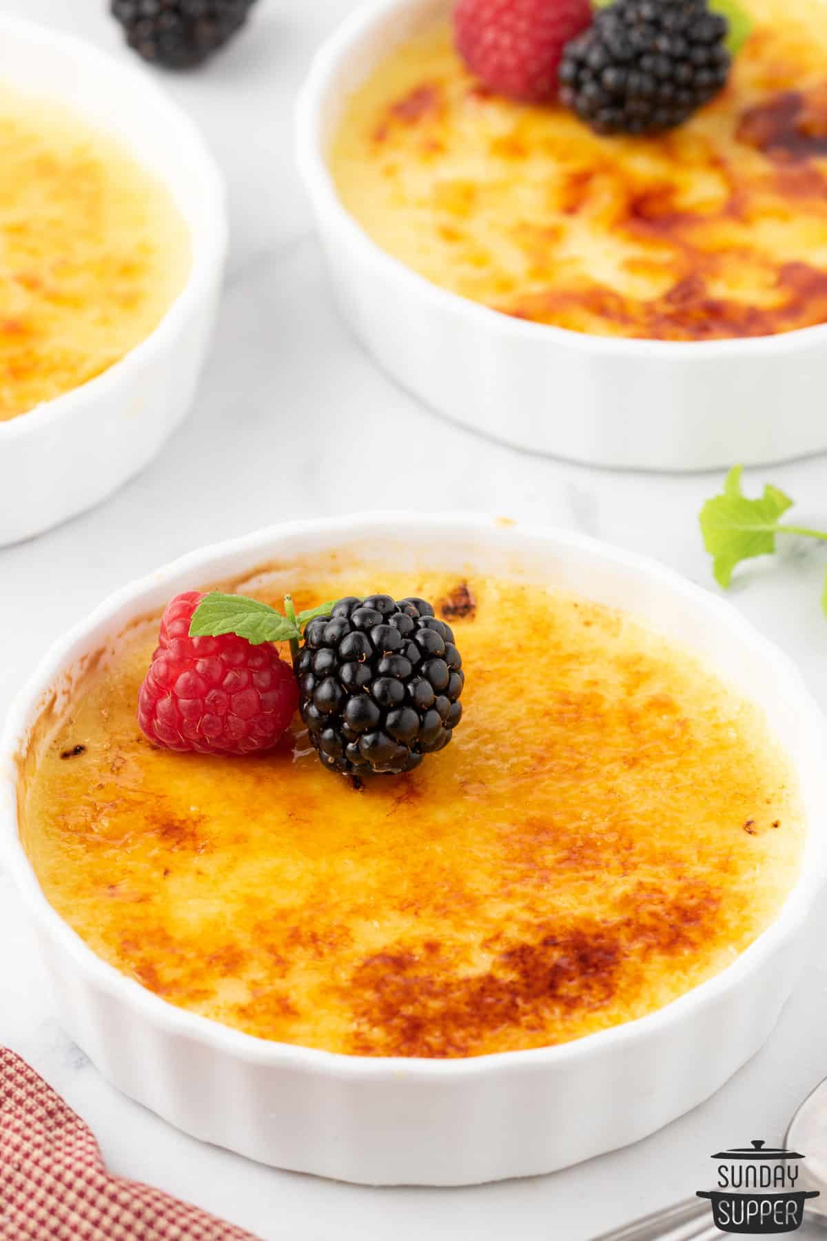 several ramekins of creme brulee with a garnish of berries