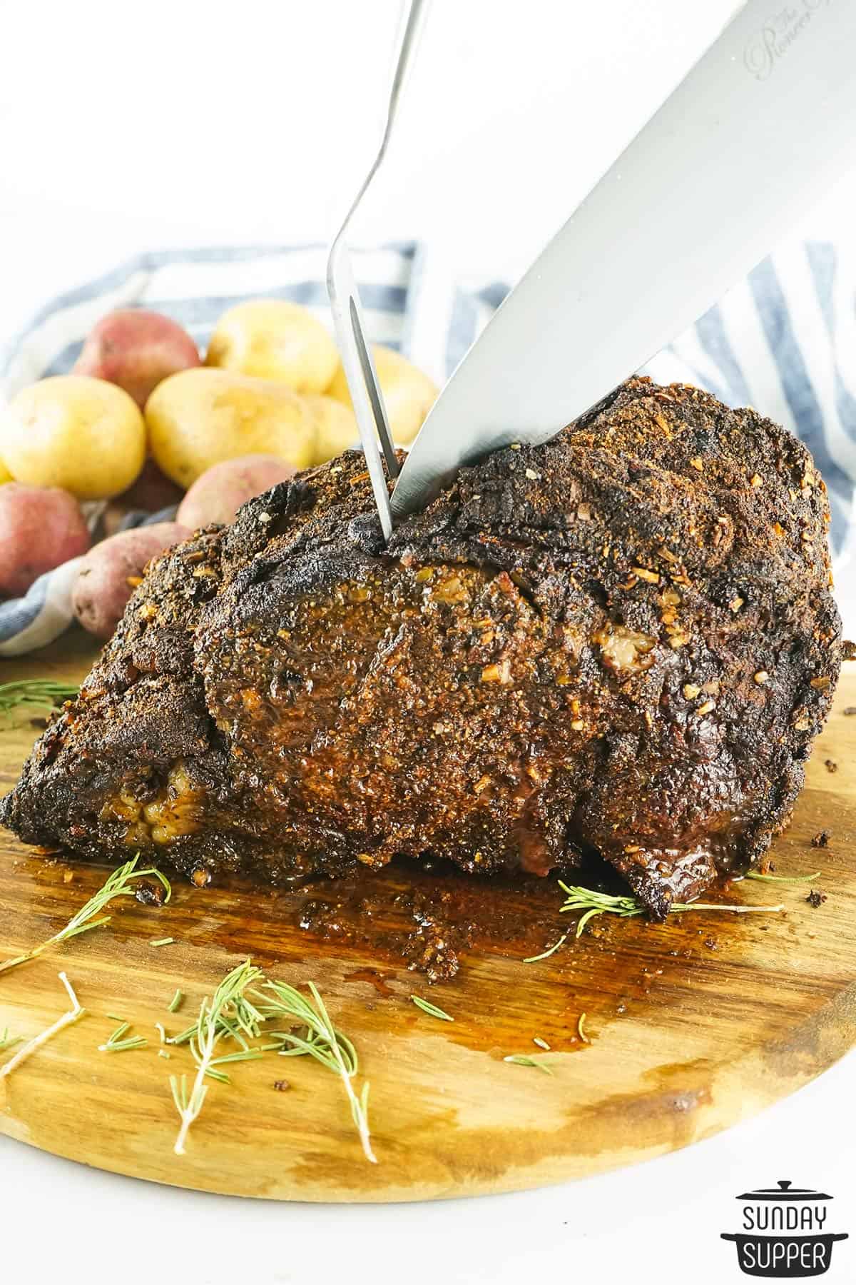 slicing prime rib on a wood cutting board