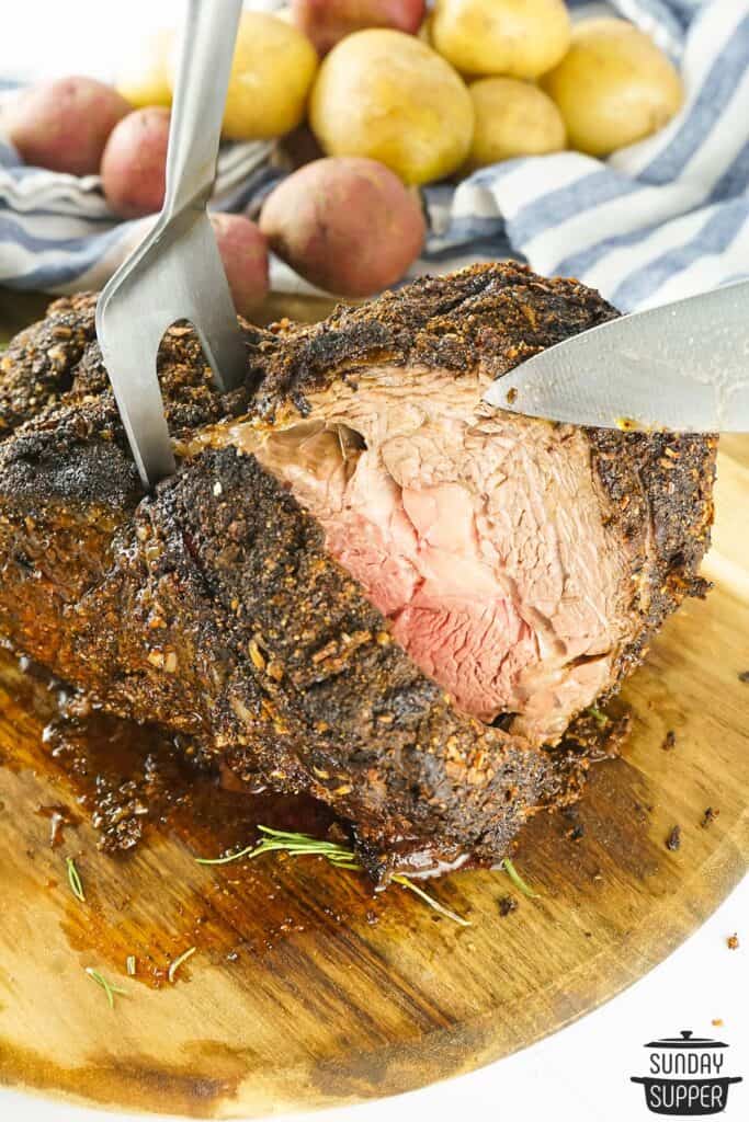 slicing grilled prime rib on a wood cutting board