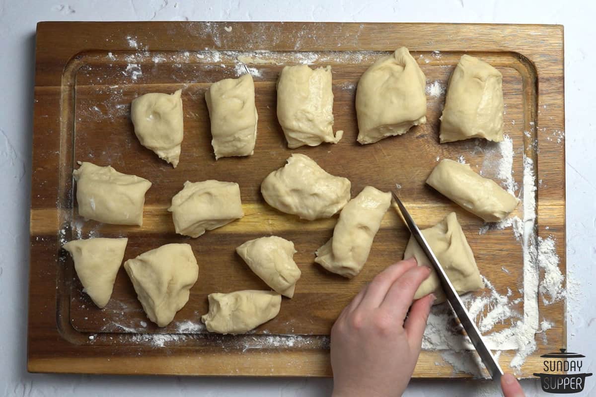 cutting dough into portions to form dinner rolls