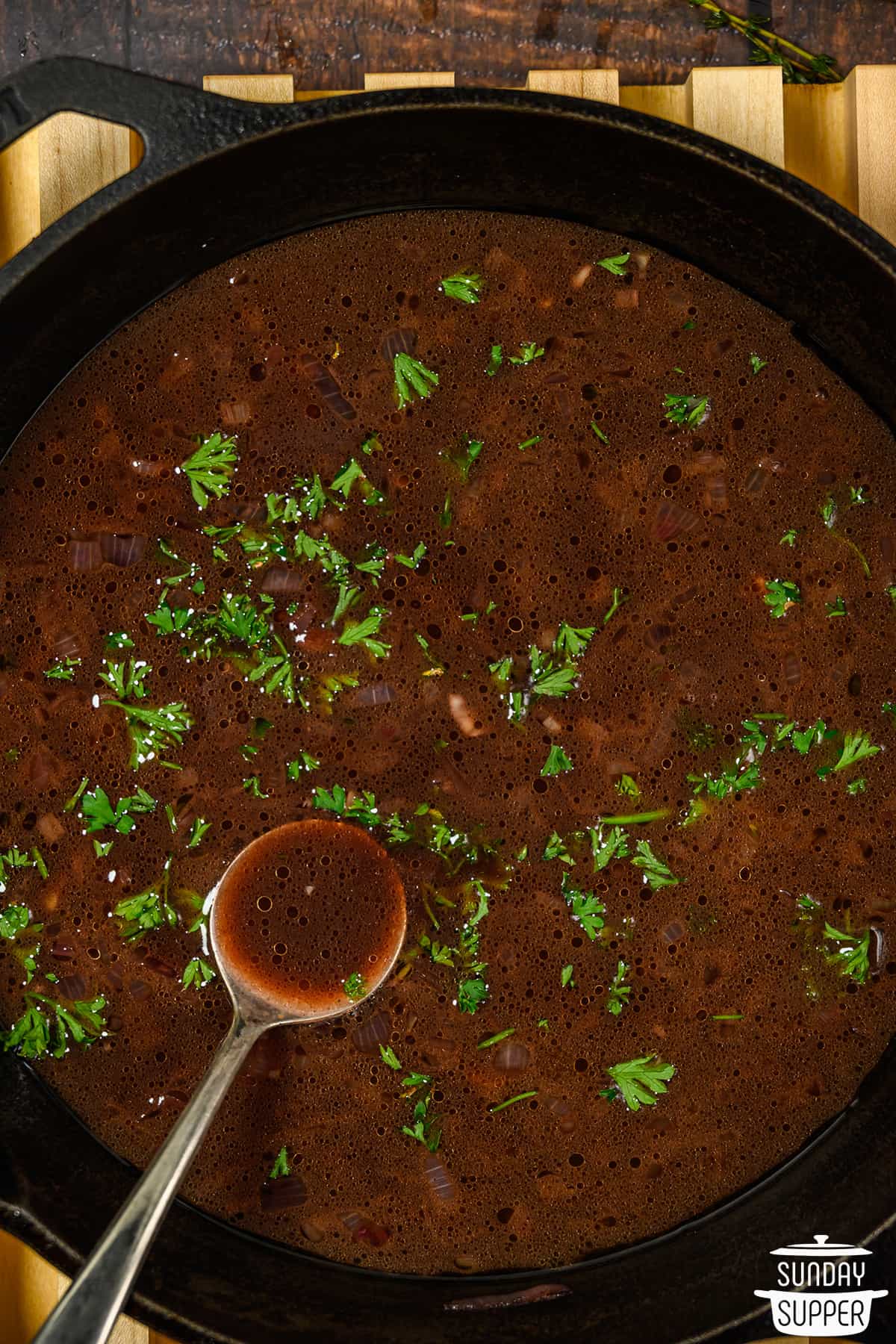 red wine reduction in a skillet with a spoon and fresh parsley