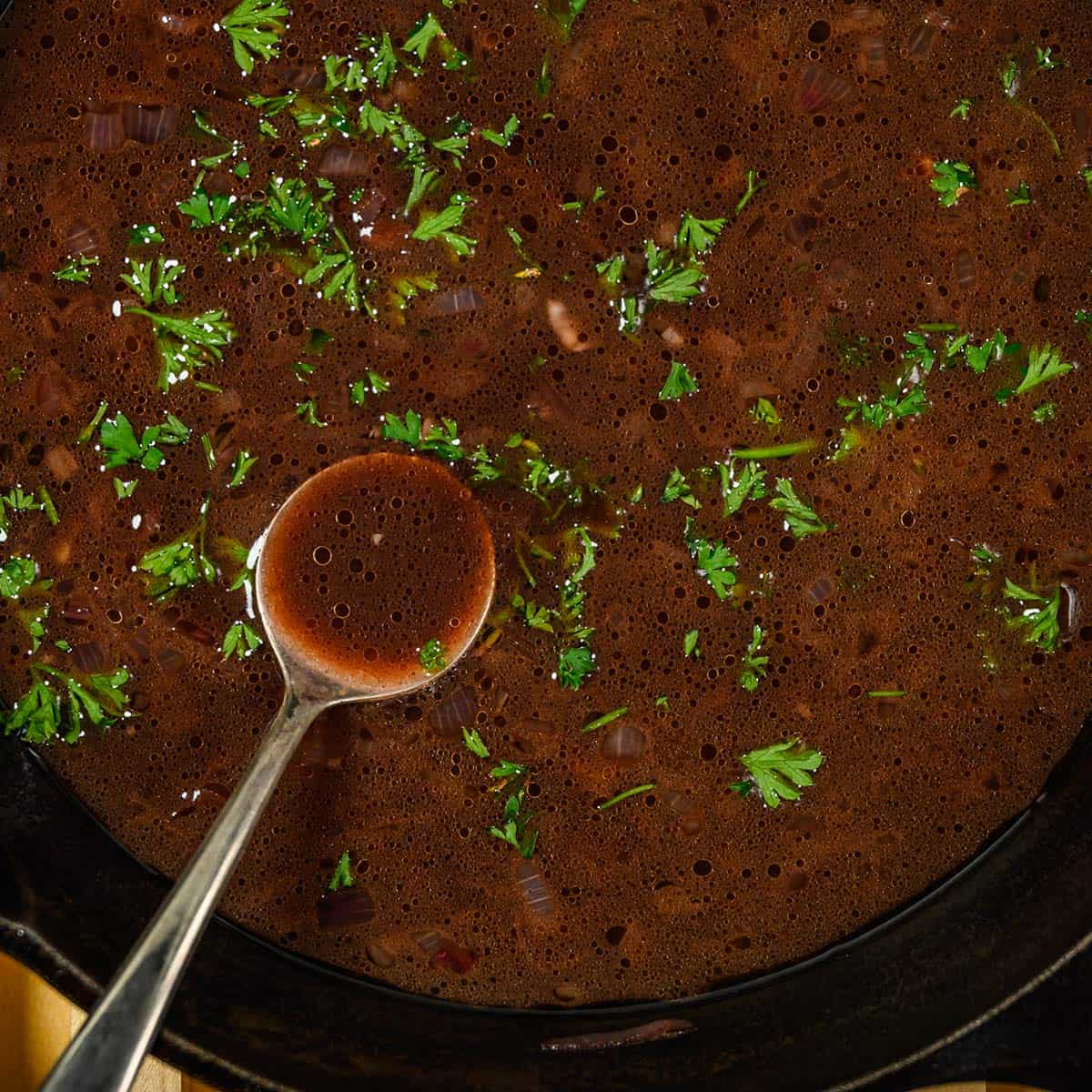 red wine reduction up close in skillet with spoon