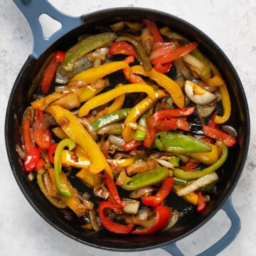 close up of a black skillet with sauteed peppers and onions