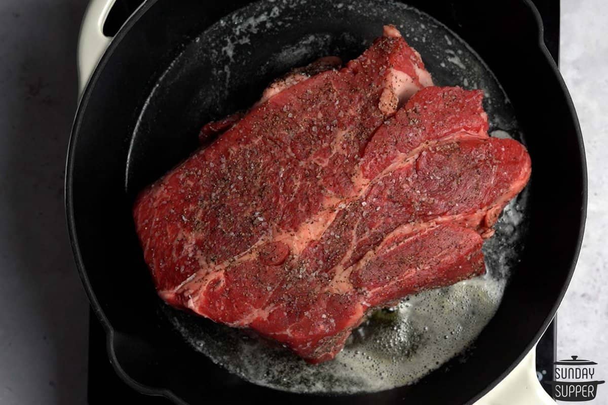 searing chuck roast beef on all sides in a skillet