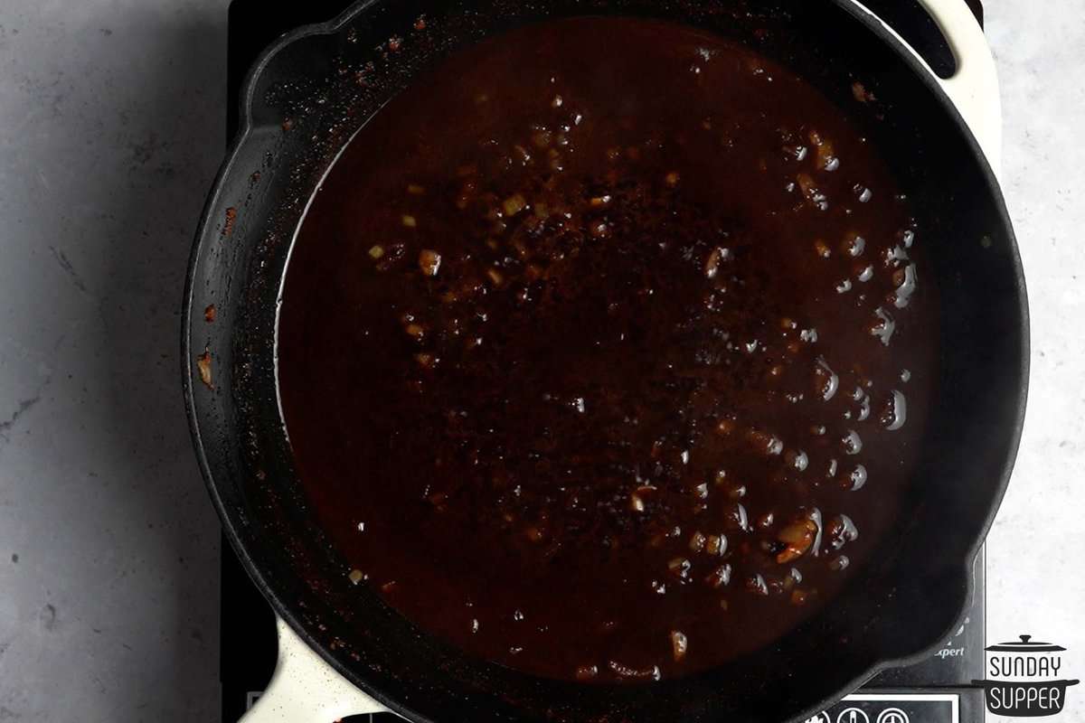 reducing red wine mixture with onions in a skillet
