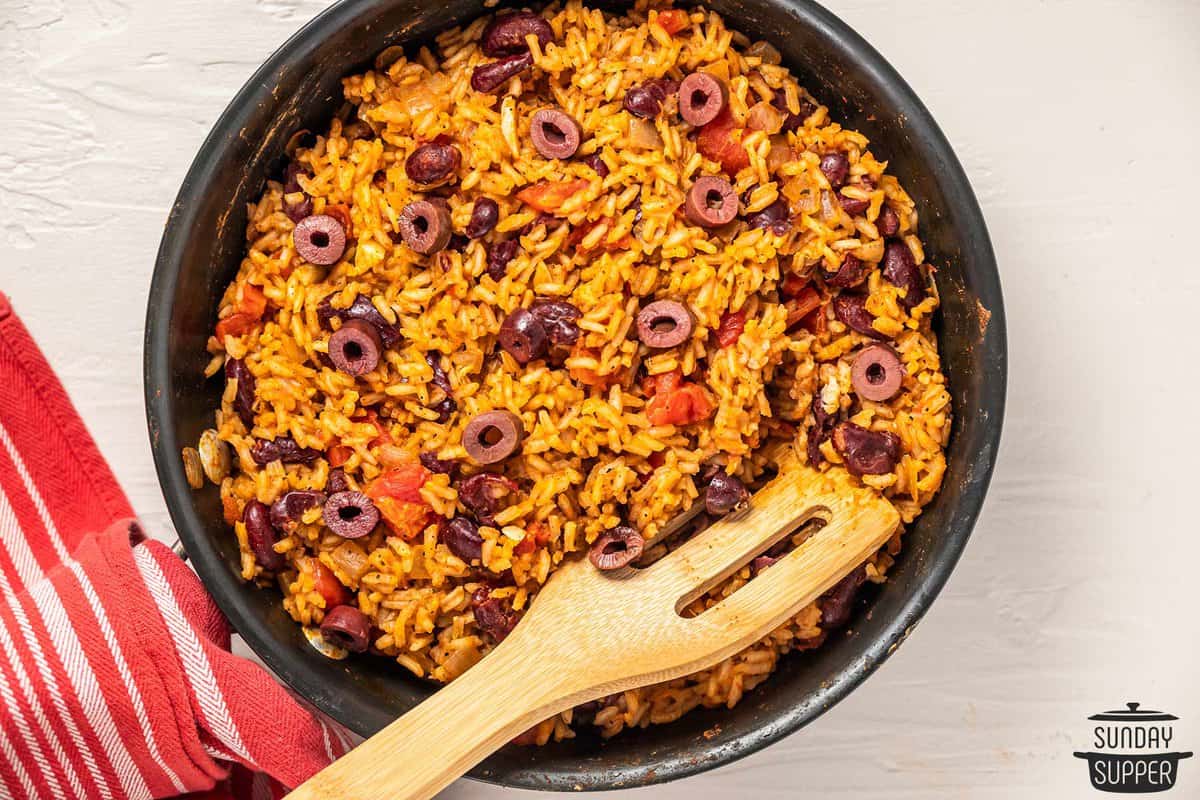 cooked rice with sliced olives in a pan