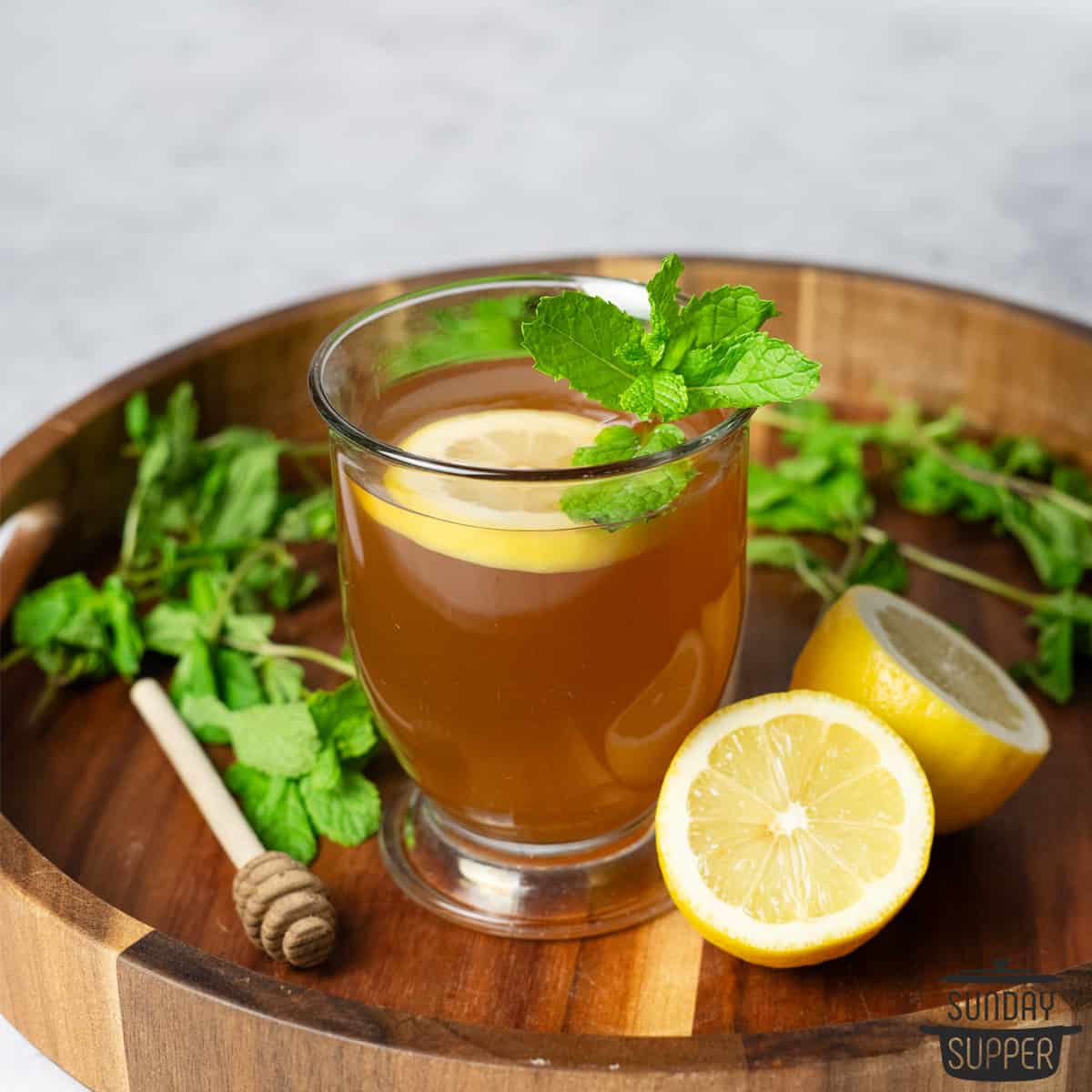 a glass of starbucks medicine ball tea with a sprig of mint and a lemon slice