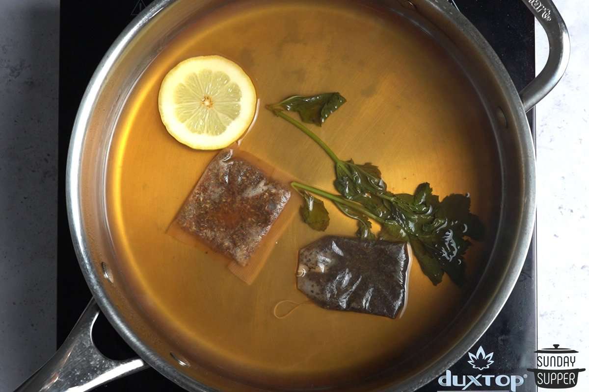 tea steeping in a pot with lemon and herbs