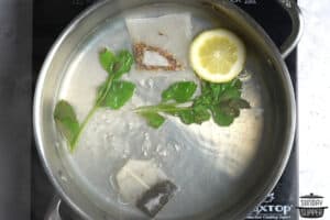boiling tea, herbs, and lemon together in a pot