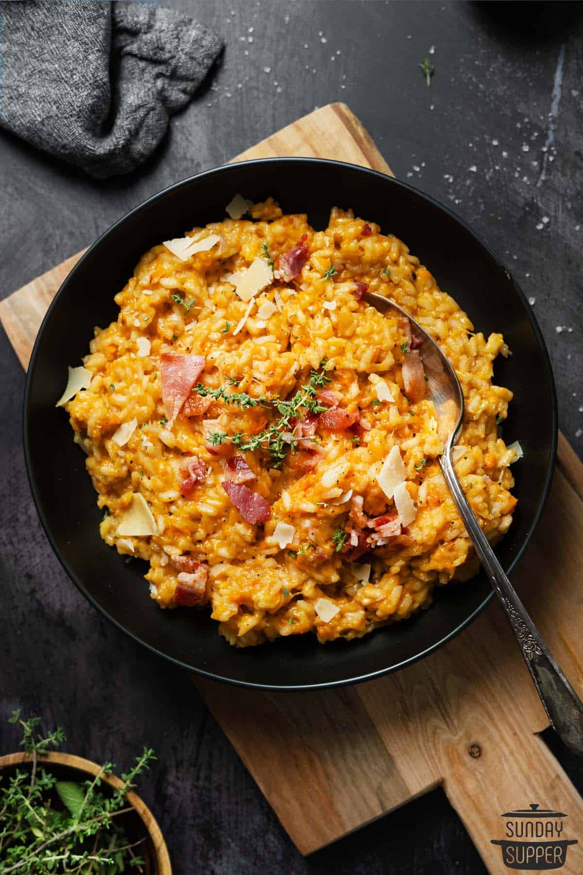 sweet potato risotto in a black bowl on a wood cutting board