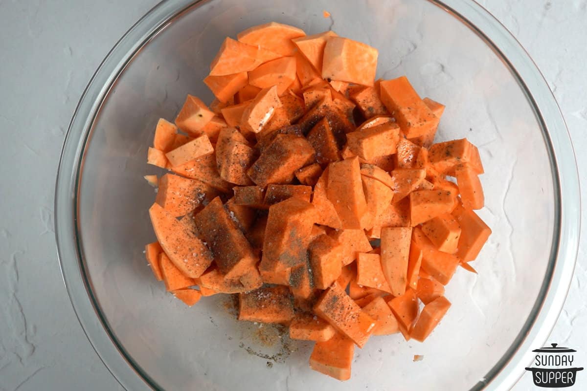adding cubed sweet potatoes in a clear bowl