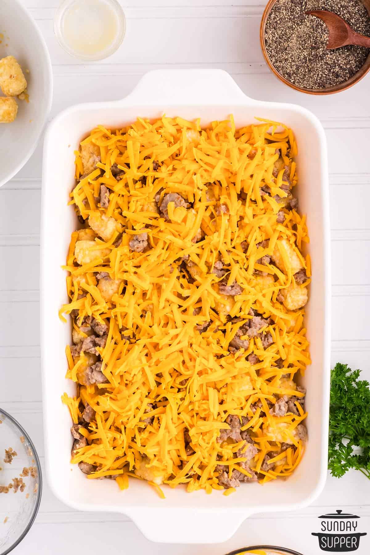 cheese, sausage, and tater tots added to the casserole dish