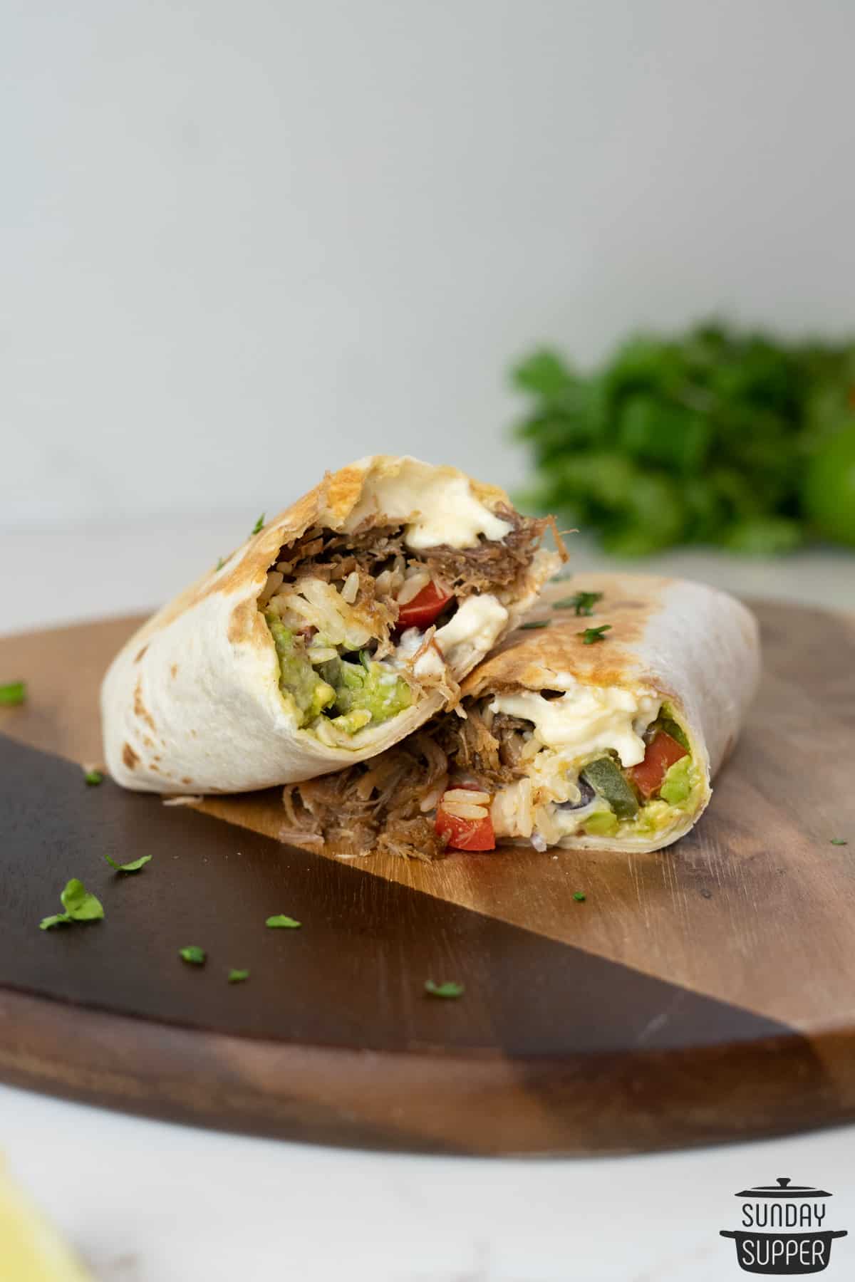 two stacked slices of carnitas burritos to show off the fillings