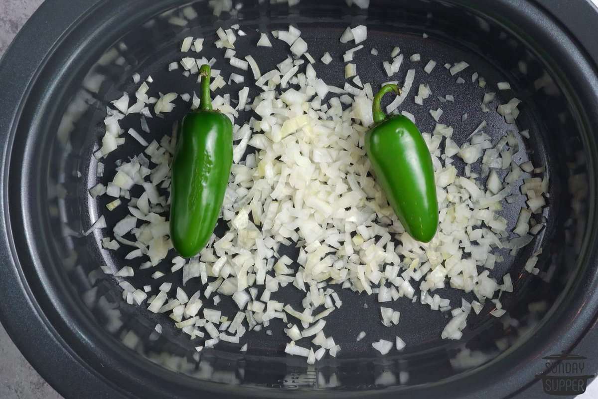 chopped onions and jalapenos placed in a slow cooker