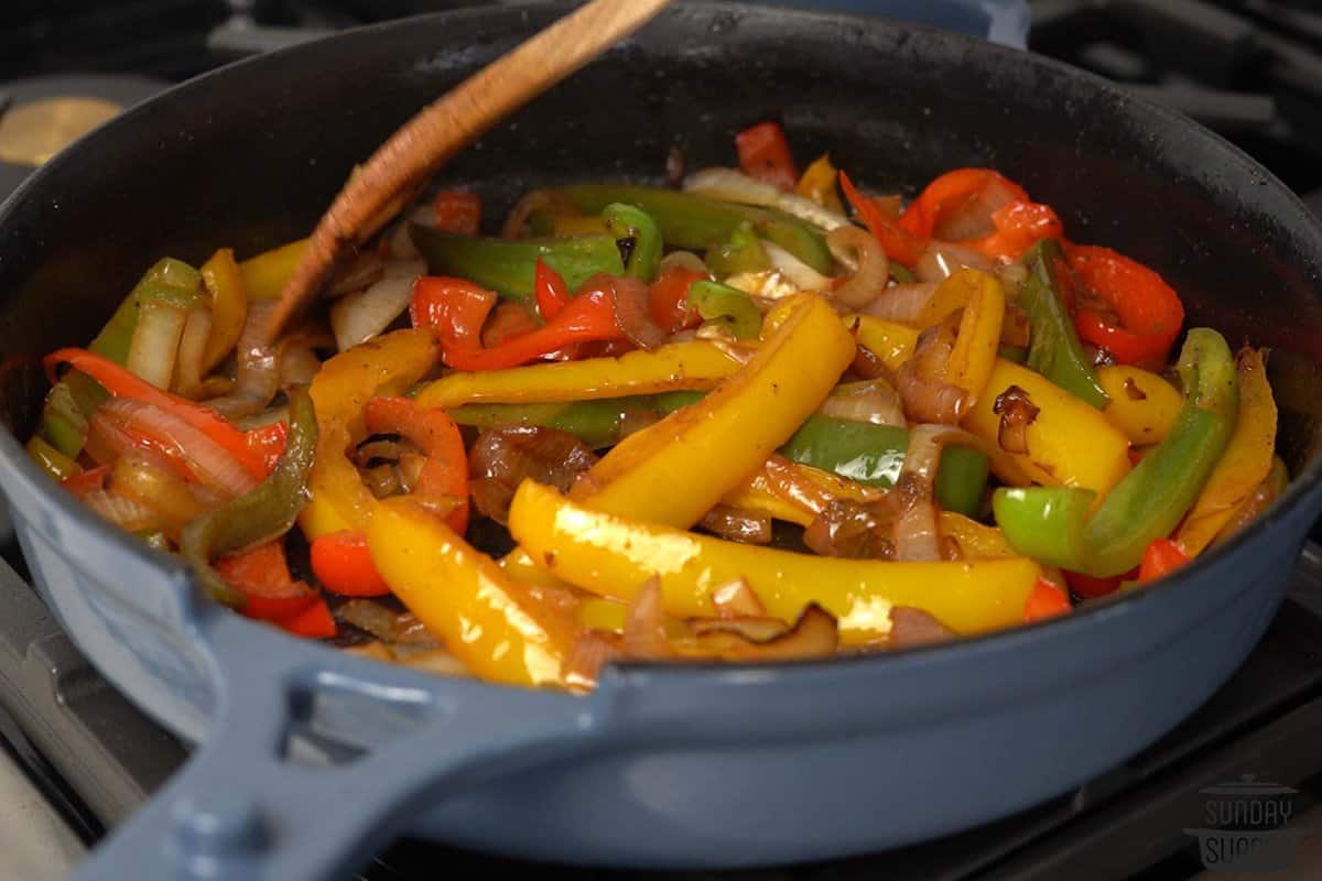 onions and peppers sauteing in a pan