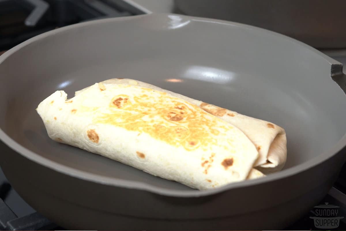 the wrapped burrito on a pan to toast