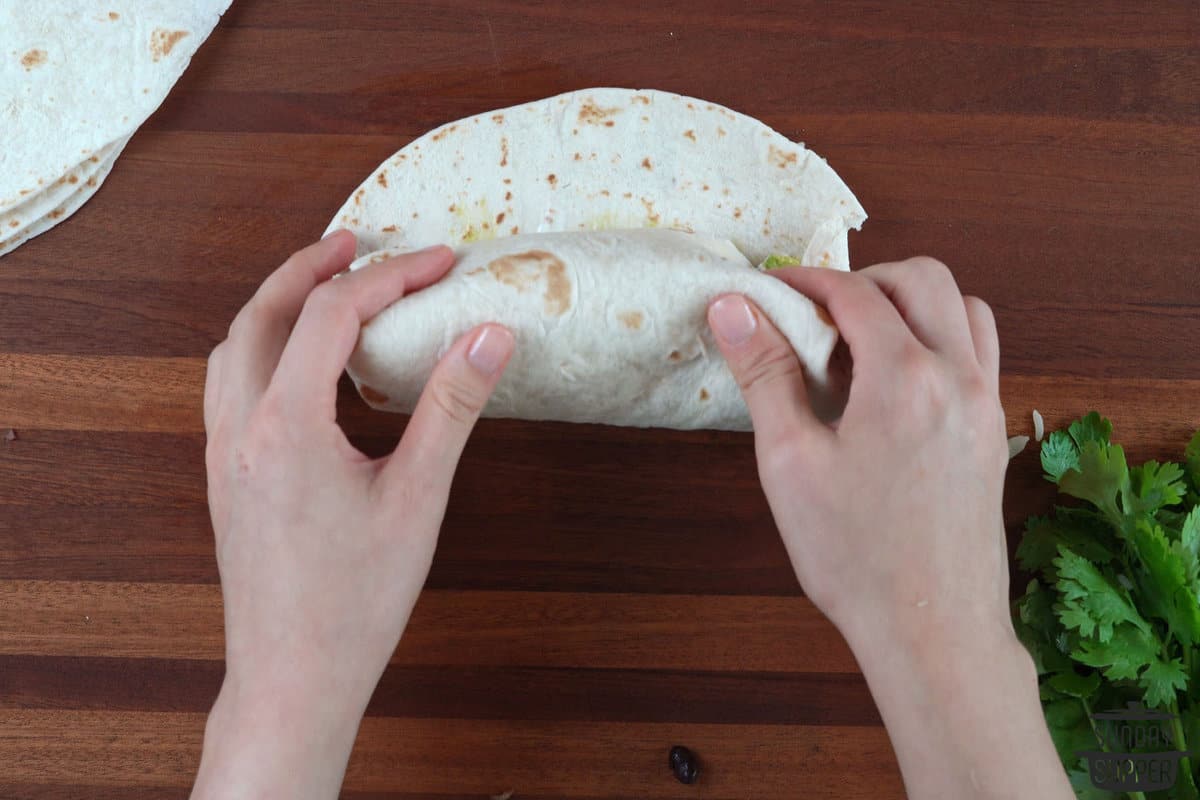 wrapping the burrito by folding the edges and rolling it