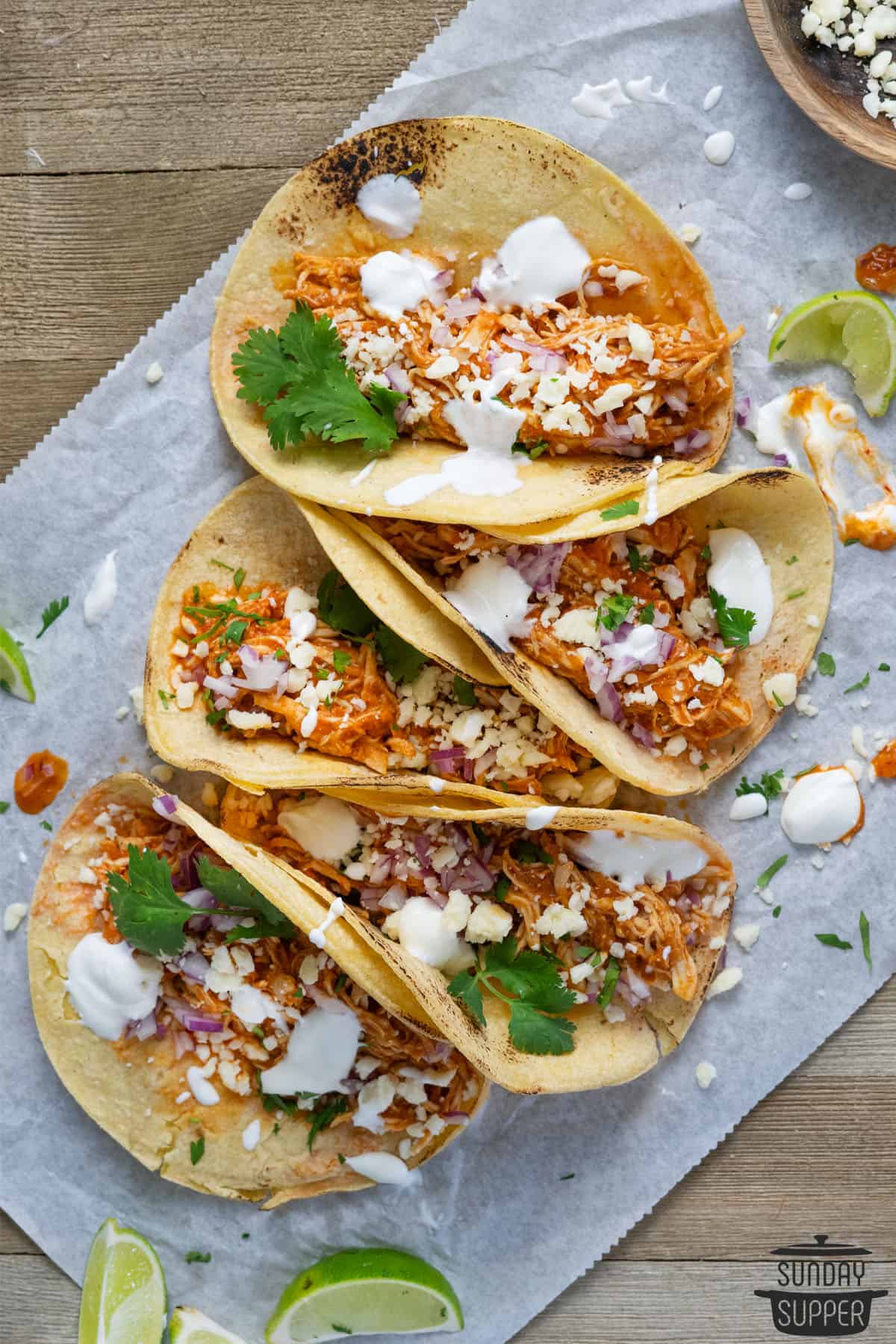 chicken tinga tacos ready to serve on parchment paper with extra lime