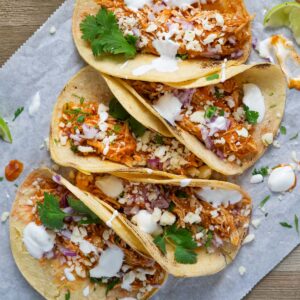five chicken tinga tacos on a slice of parchment paper