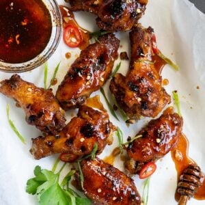 Instant pot wings lined on parchment paper with honey sriracha sauce
