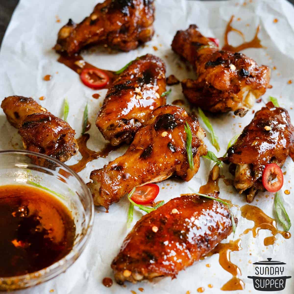 Parchment paper with instant pot chicken wings covered in honey sriracha sauce