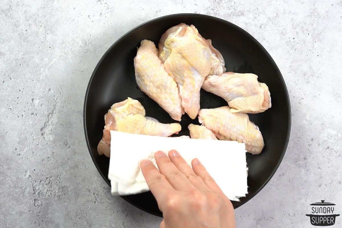 patting chicken wings dry with a towel
