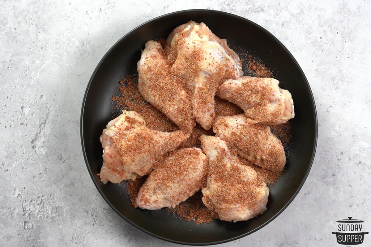 Seasoning chicken wings in a bowl