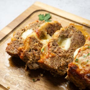 a cutting board with cooked italian meatloaf sliced on it