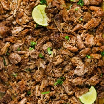 close up of pork carnitas with limes