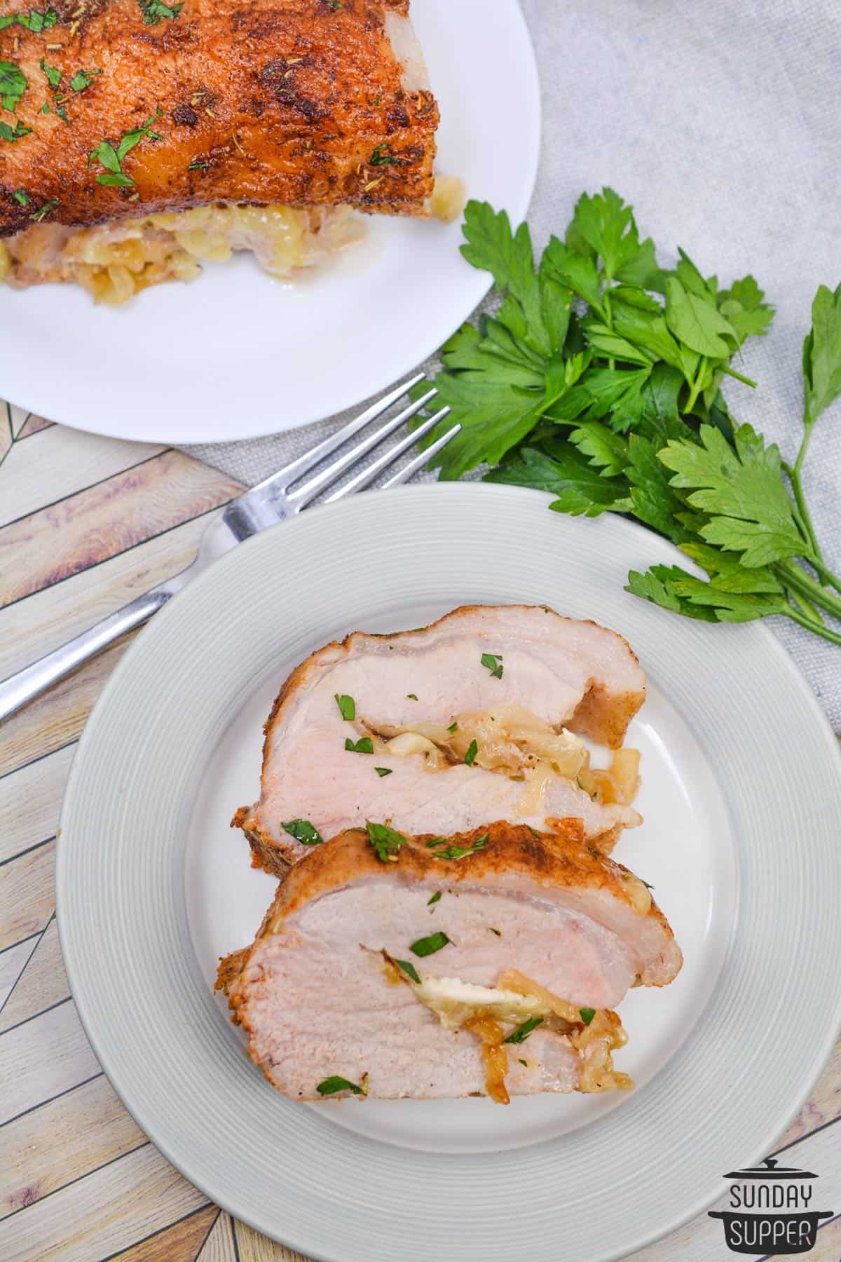 slices of stuffed pork tenderloin on a dinner plate with extra parsley