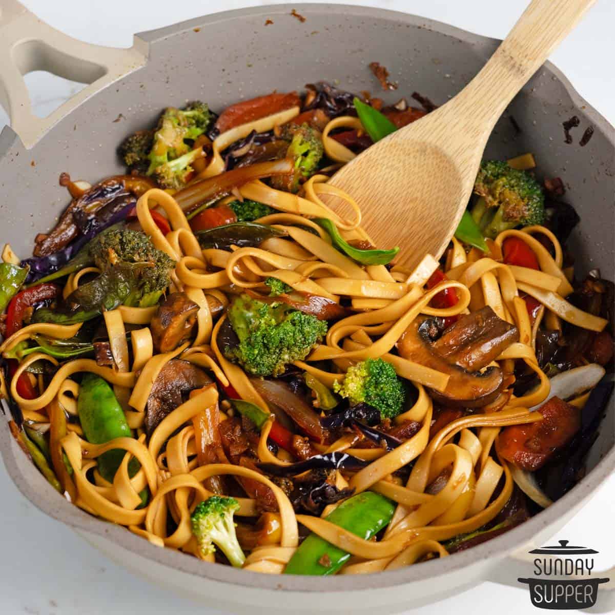 vegetable stir fry in a skillet with a wooden spoon inside
