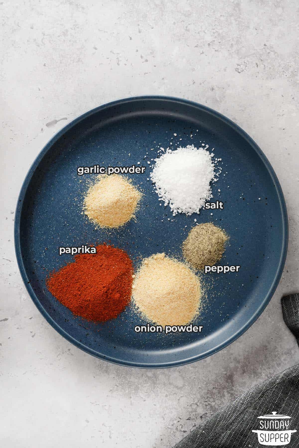the ingredients for burger seasoning in small piles on a plate