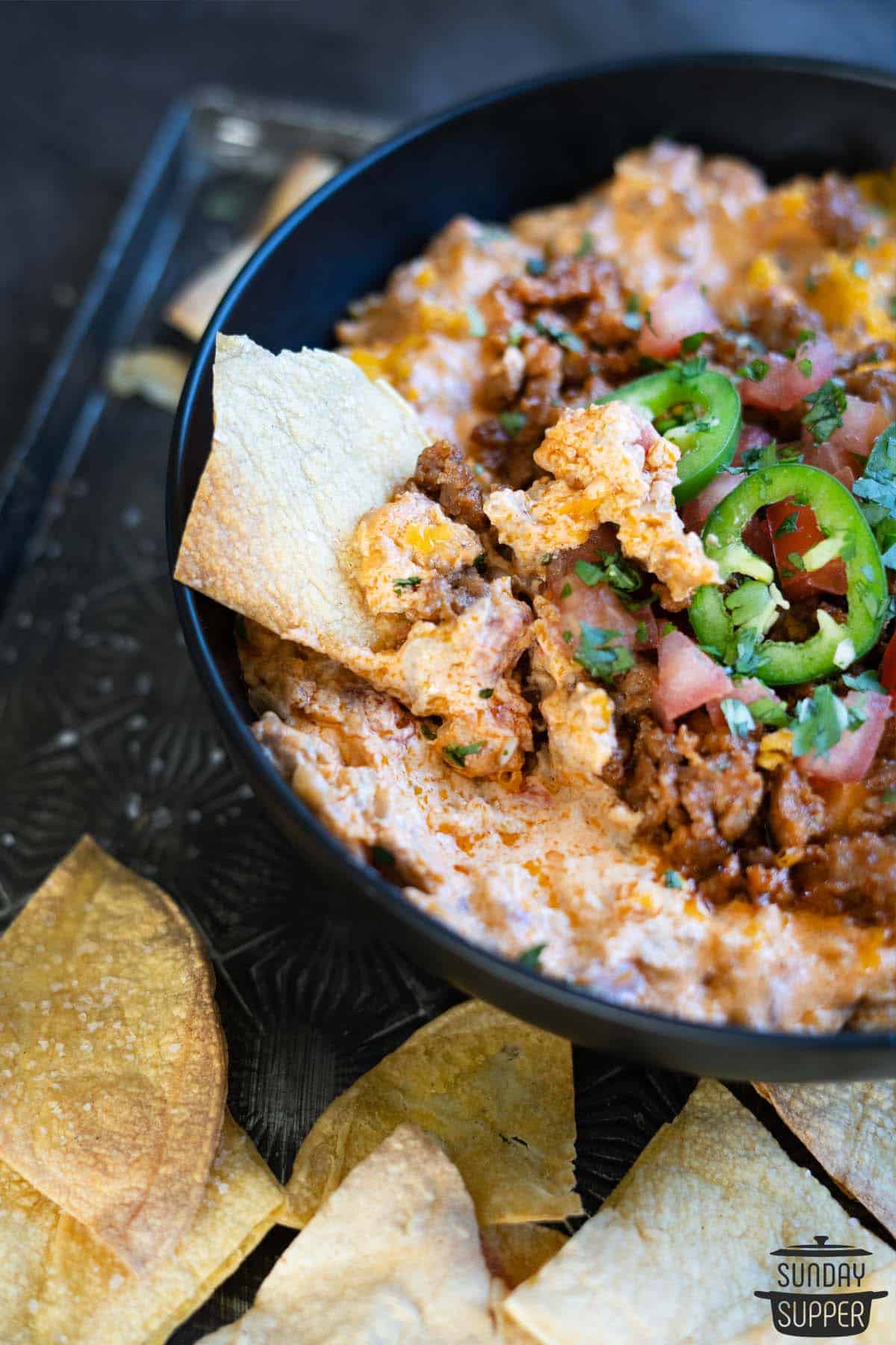 a chip dipped into the bowl of chorizo cheese dip