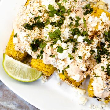 corn on a plate covered in elote seasonings with lime