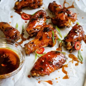 a platter of chicken wings and drumsticks coated in honey sriracha sauce