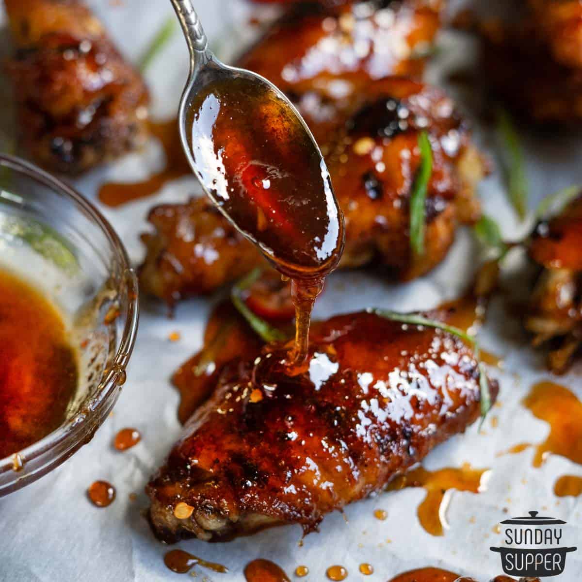 a closeup of a spoon pouring honey over a chicken wing