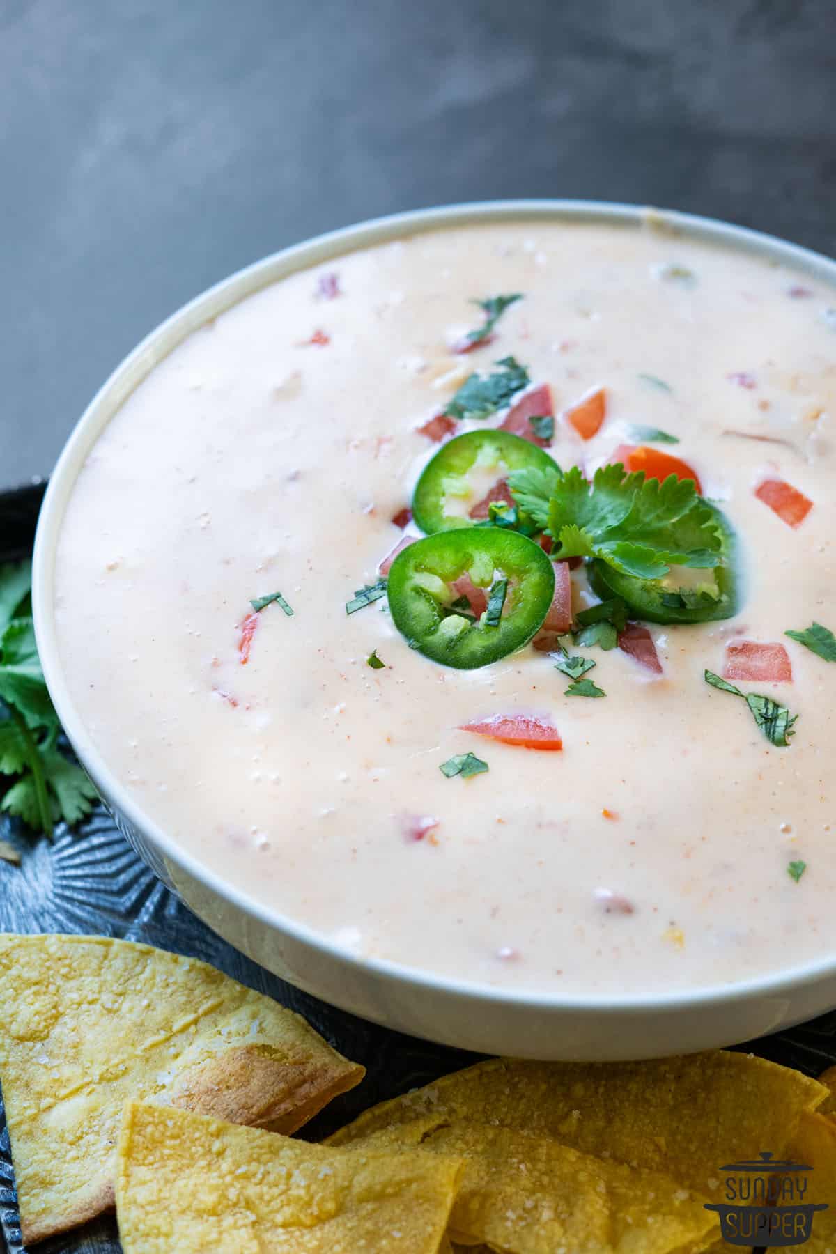 a bowl filled with queso blanco and topped with cilantro and jalapenos