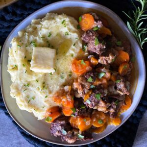 a dinner plate with half mashed potatoes and half braised short ribs
