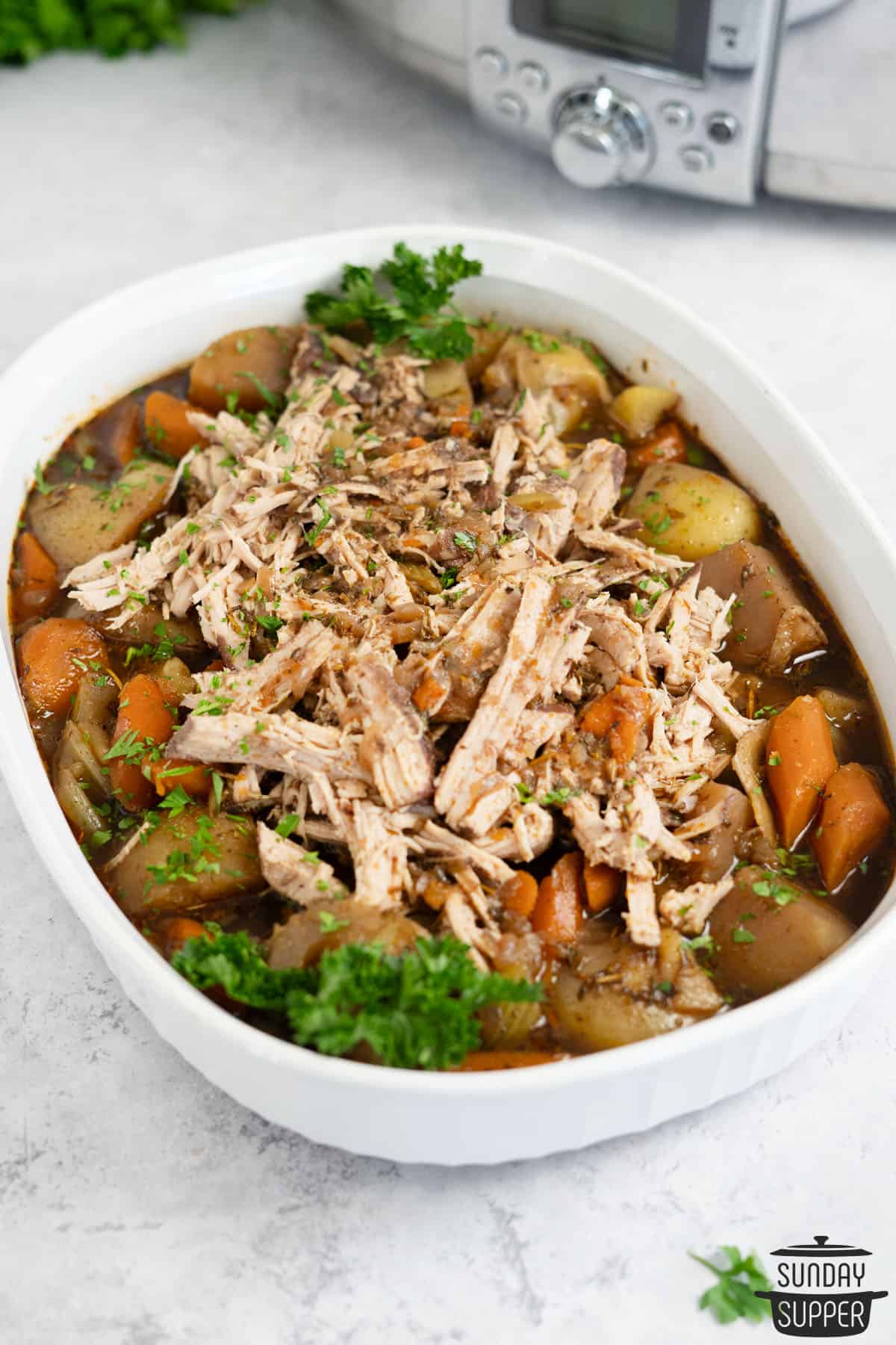 shredded pork pot roast in a serving bowl with vegetables and gravy