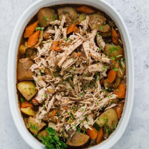 pork roast shredded in a serving bowl with potatoes and carrots